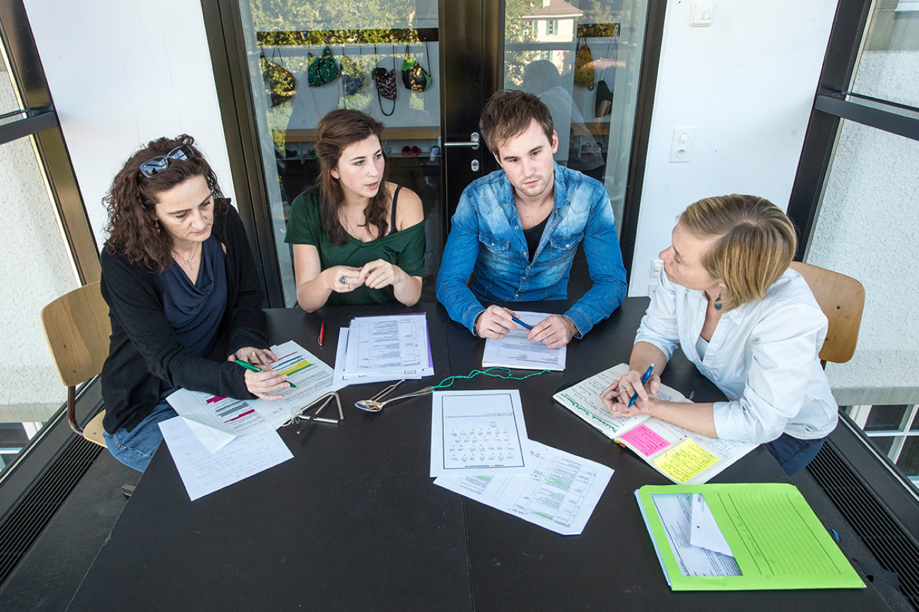 Studierende sitzen mit einer Praxislehrerin und einer Dozentin der PHBern an einem Tisch und diskutieren den Unterricht.
